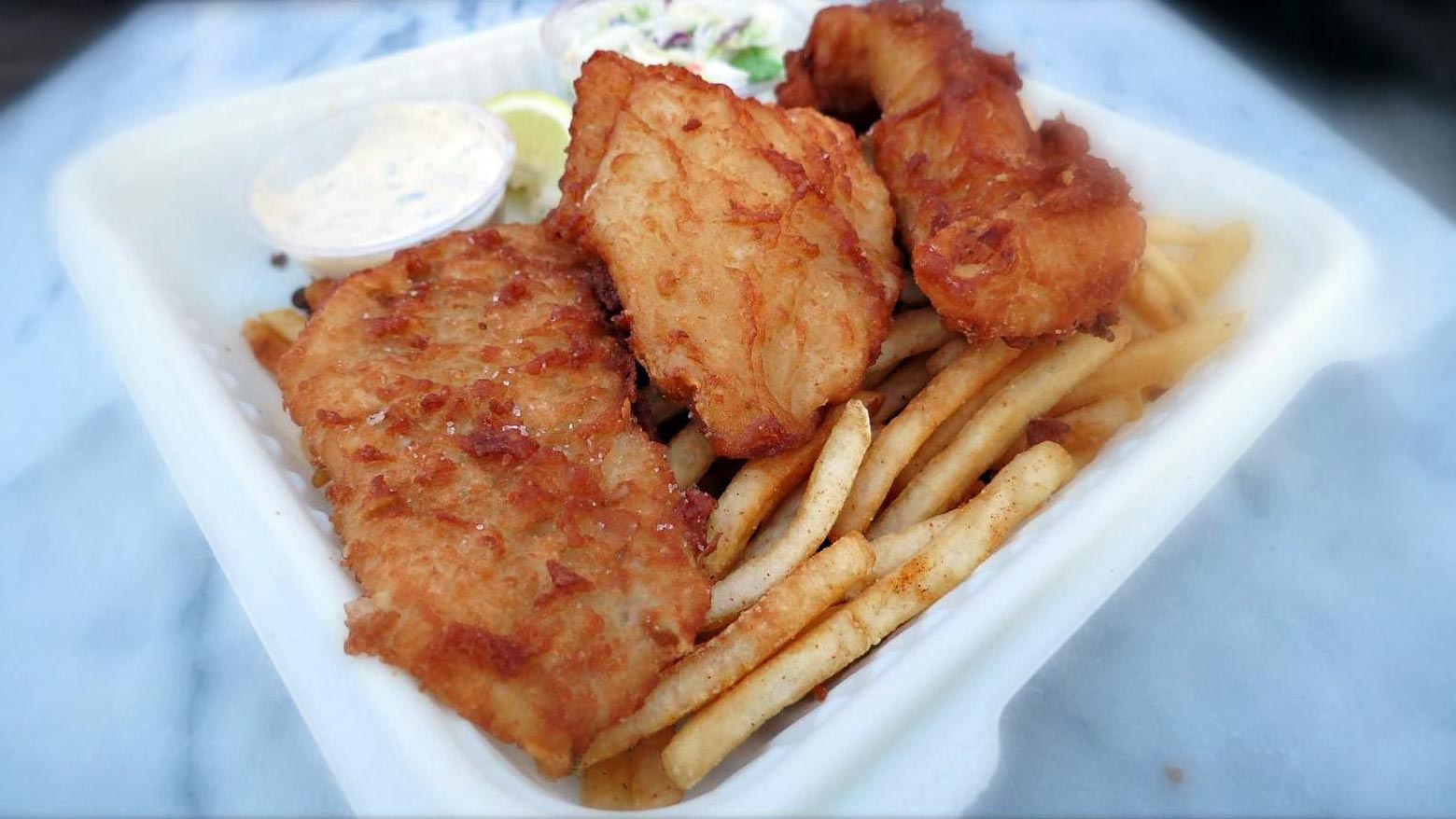 closeup of fish and chips with Old Bay french fries and coleslaw from Sam's ChowderMobile
