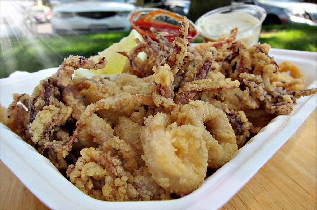 closeup of fried calamari with cocktail sauce and tartar sauce