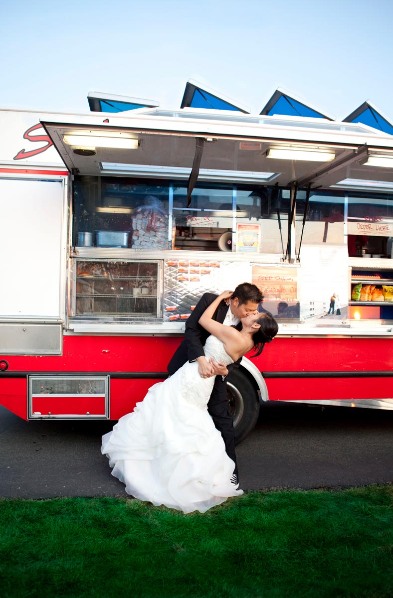 newlyweds pose for a dramatic kiss in front of Sam's ChowderMobile at their catered wedding reception