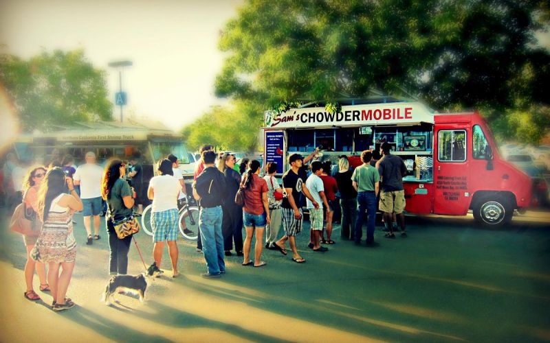 line of people eagerly waiting to order seafood from Sam's ChowderMobile food truck at evening food truck event