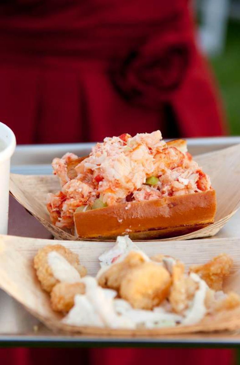 closeup of wedding guest holding reception dinner tray with clam chowder, shortie lobster roll, and spicy popcorn shrimp