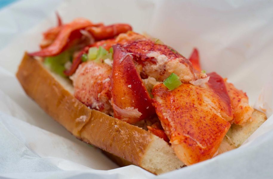 closeup of Sam's ChowderMobile famous Lobster Roll sandwich shows lots of fresh Maine lobster lightly tossed in warmed butter on a toasted bun