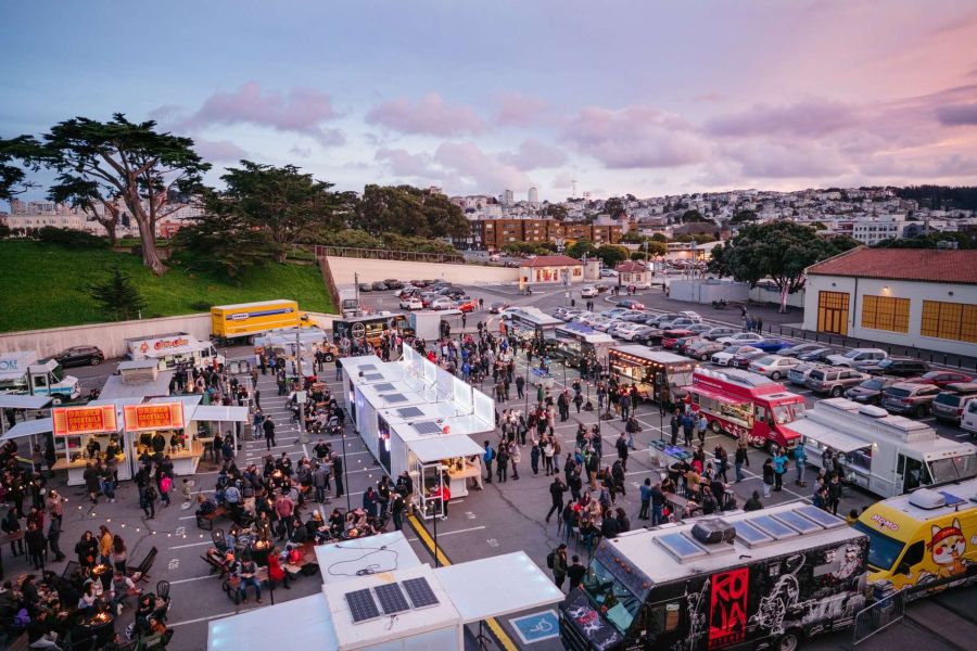 food trucks serving in San Francisco neighborhood parking lot during event at dusk
