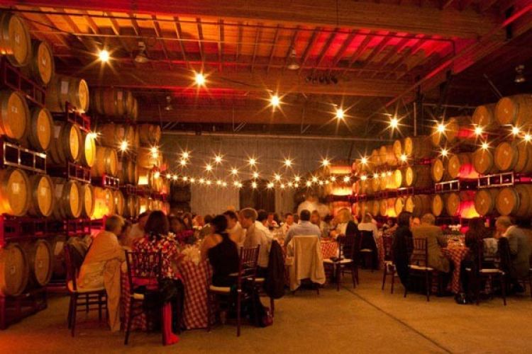 tables full of guests ast wine cave lit up at night for evening catered seafood dinner at San Francisco Bay Area winery event